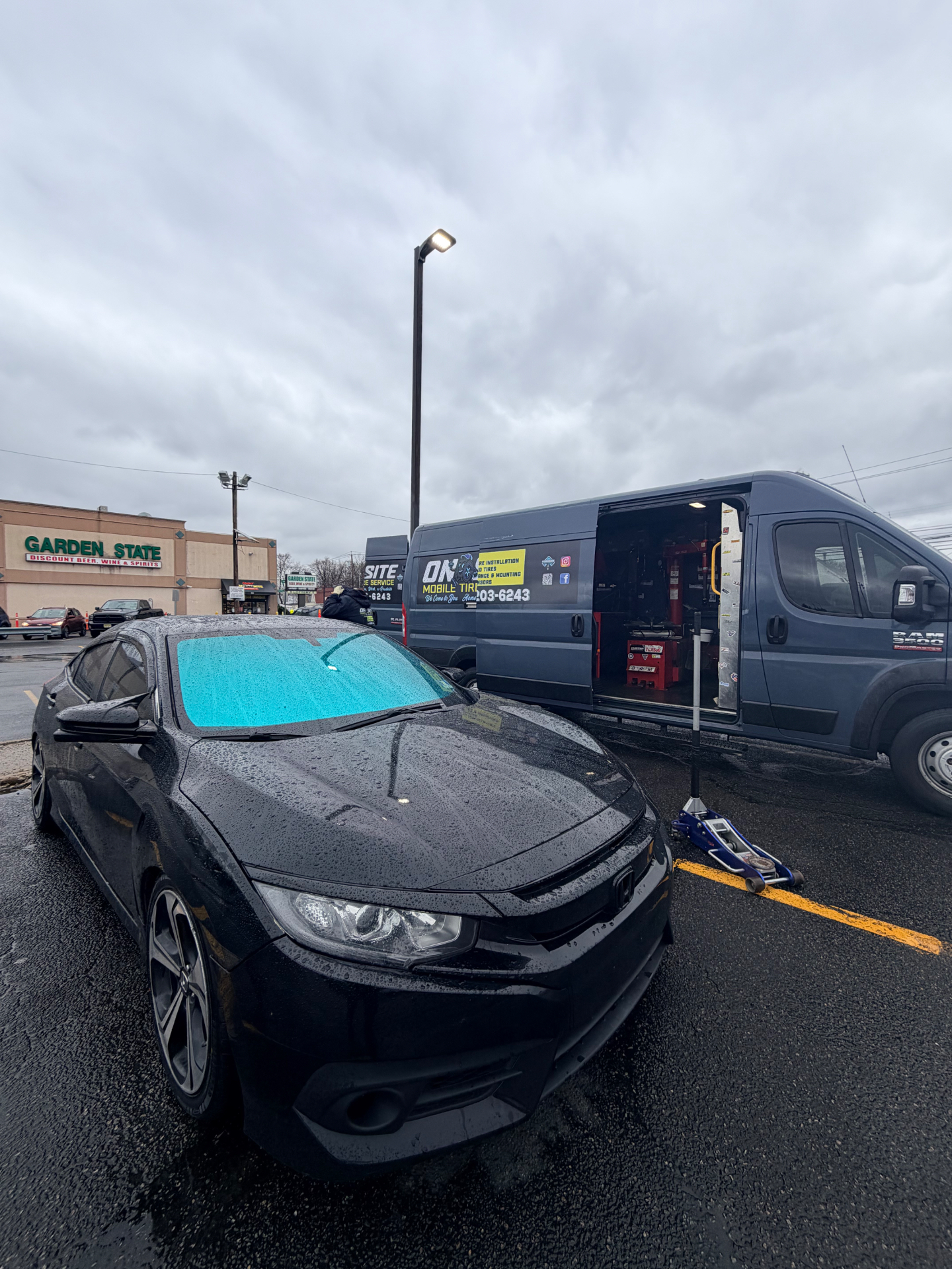 Black Honda Civic on a floor jack next to the On-Site Mobile Tire Service van in a NJ parking lot