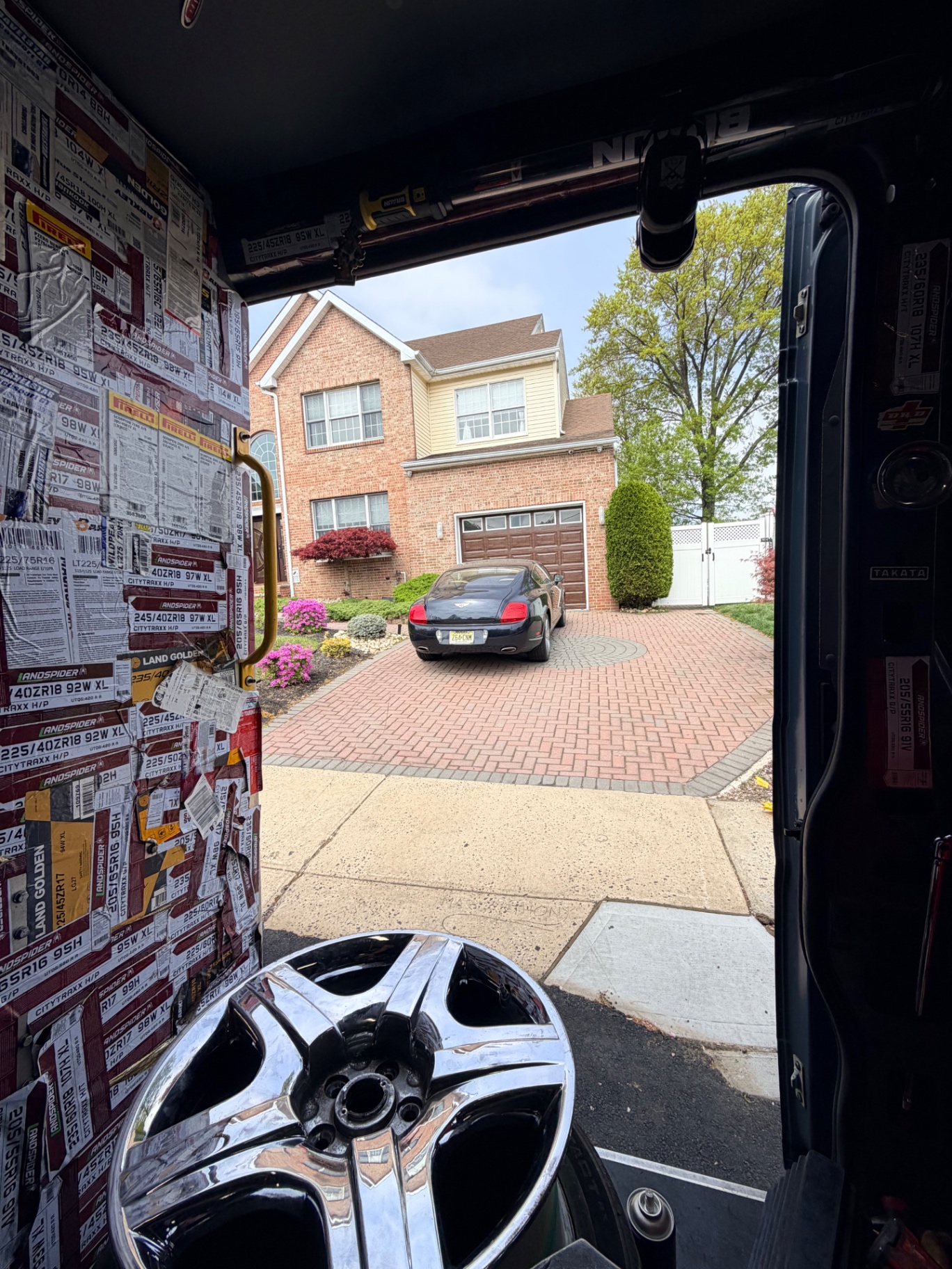 View from inside the mobile tire van of a Bentley Continental on a brick driveway in front of a NJ home
