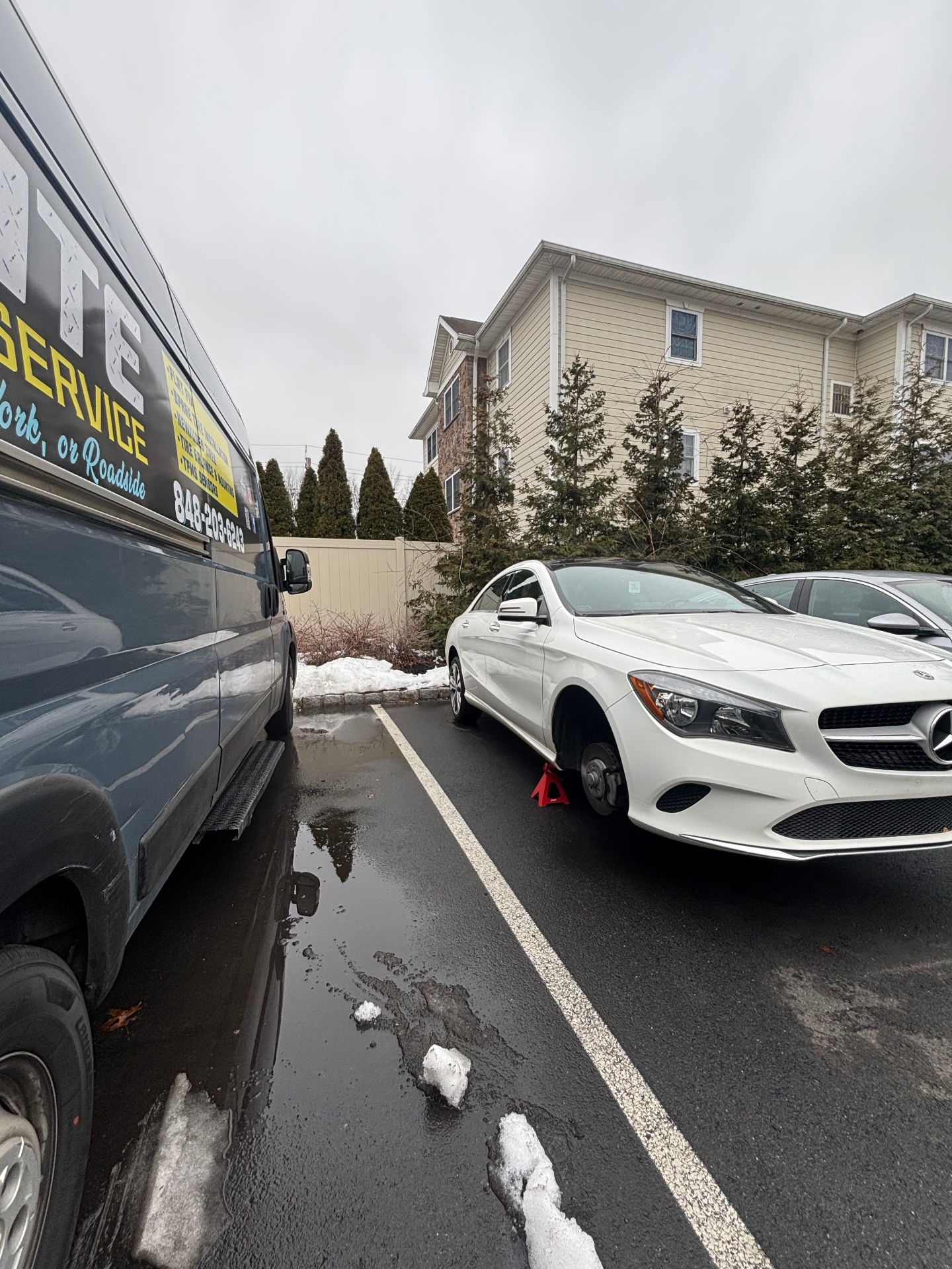 White Mercedes-Benz CLA with wheel removed on a jack stand next to the On-Site Mobile Tire Service van
