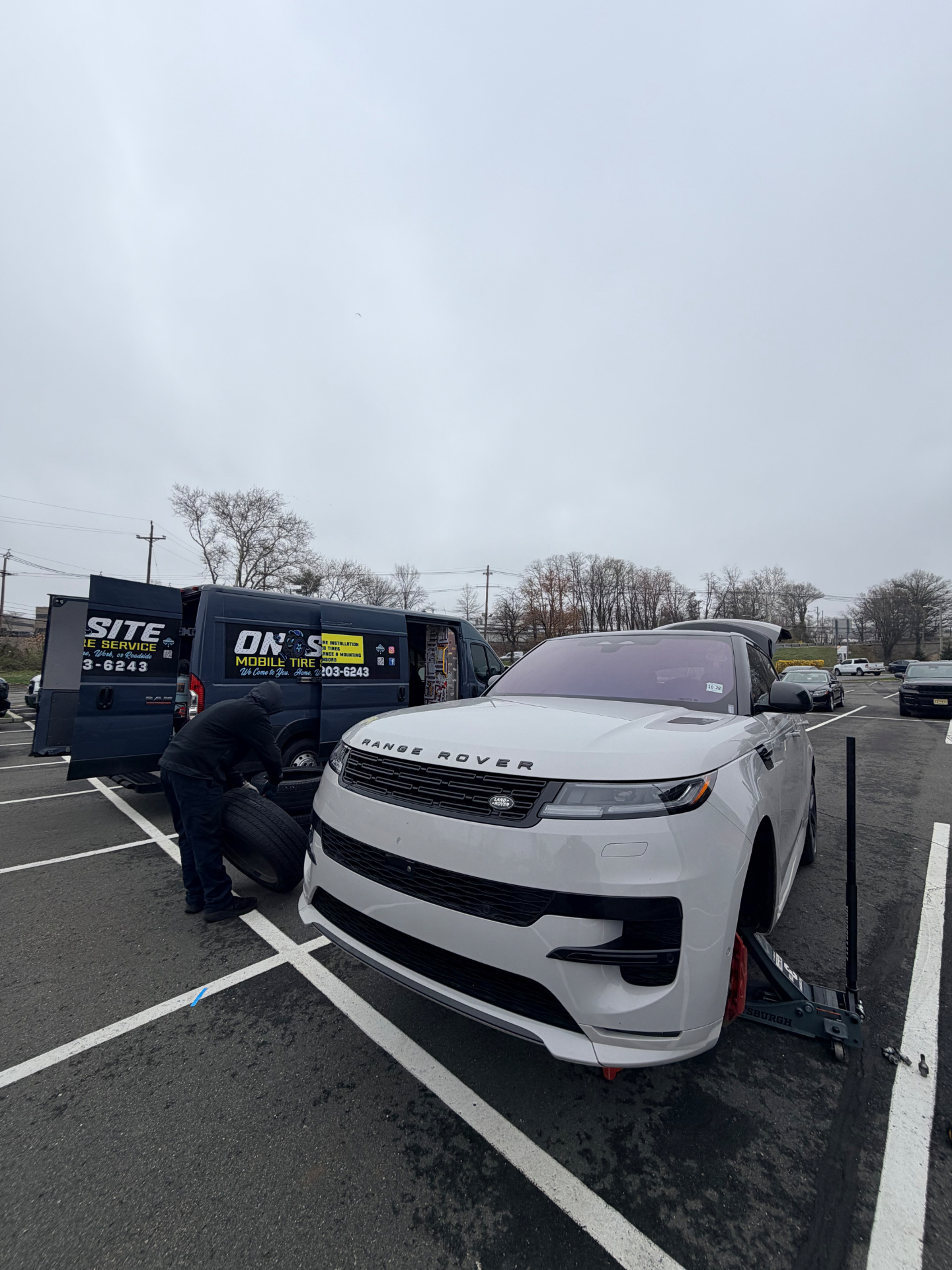 On-Site Mobile Tire Service van swapping a tire on a white Range Rover Sport in a New Jersey parking lot