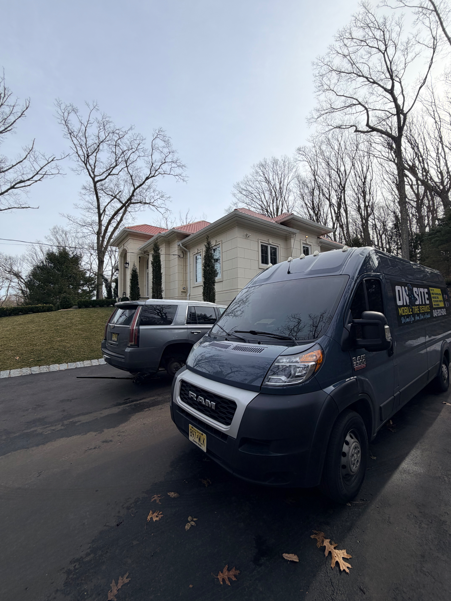 On-Site Mobile Tire Service Ram ProMaster van parked at a NJ mansion servicing a Cadillac Escalade