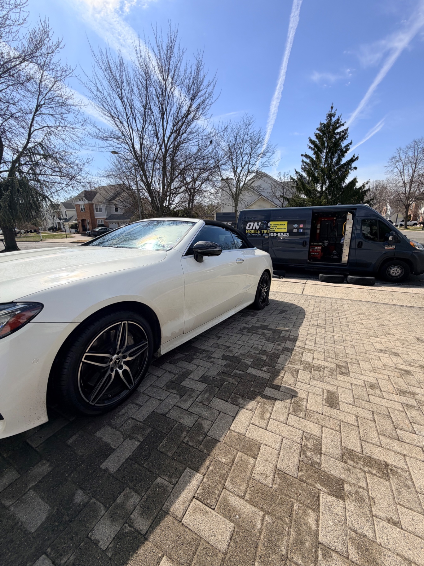 White Mercedes-Benz C-Class cabriolet on a brick driveway with the On-Site Mobile Tire Service van in the background